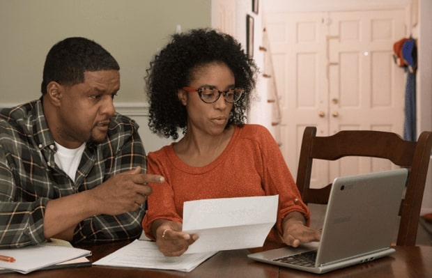 A couple look intently at a laptop while going through their mail